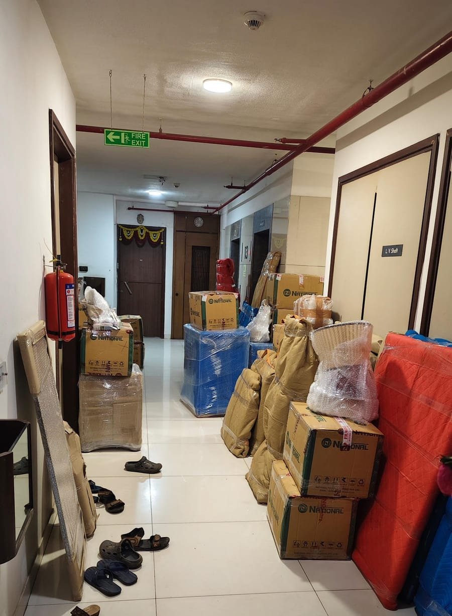 A building corridor filled with packed cartons and wrapped household items ready to move