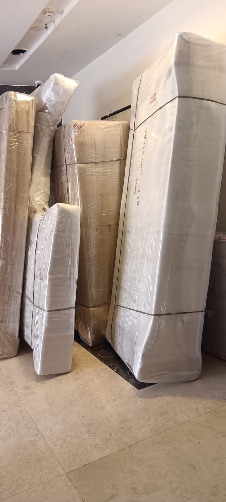 Tall pieces of furniture wrapped in stretch film and paper, labelled and stacked