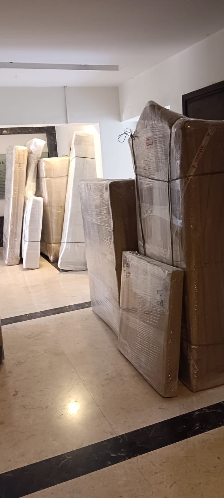 Wrapped and protected furniture pieces standing ready in a building lobby